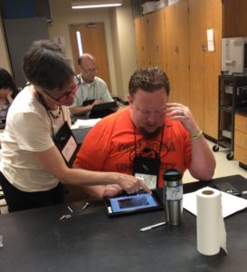 Photo of mini workshop presenter working with attendee on an iPad