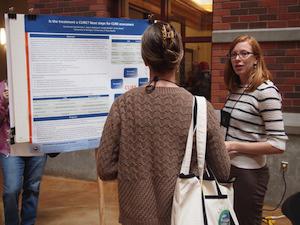 Photo of Lisa explaining her poster to an attendee