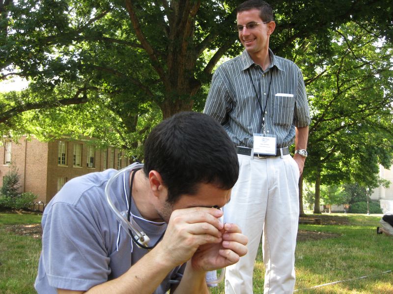 Photo of John S. looking through hand lens at an ant at his 2012 Major Workshop